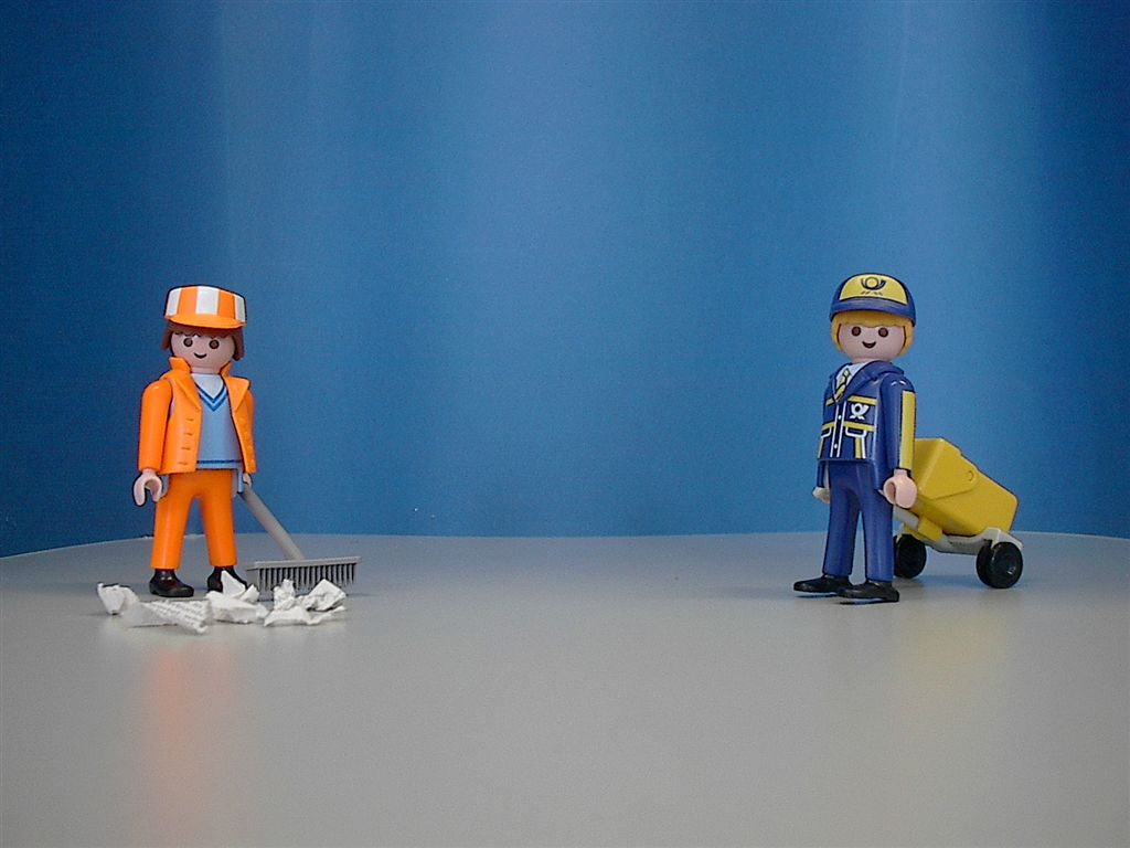 Photo of two Playmobil figures. On the left, a street sweeper with a broom and, on the right, a postman with a trolley.